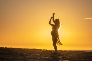 Silhouette of a pregnant women standing on a beach at sunset, symbolizing the empowerment of fertility choices for single women